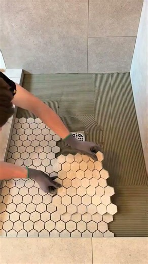 The process of installing a small-format ceramic tile pattern on the bathroom floor of the building.