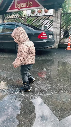 Toddler Splashes Joyfully in Puddle on Rainy Day