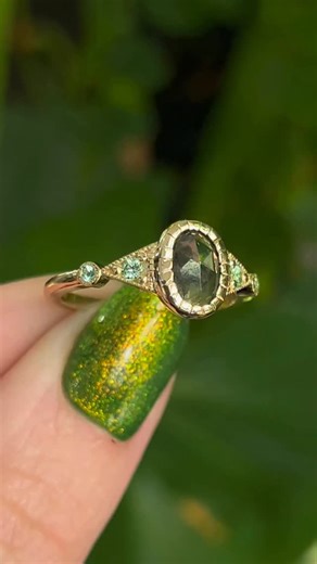 4.2K views · 142 reactions | 者✨ a custom-made yellow gold engagement ring with a bezel set 0.98ct oval rose cut green Madagascar sapphire, round lab-grown green sapphires accents, milgrain, and notches around the bezel #uniqueengagementrings #sapphireengagementring #alternativeengagementring #customengagementring | Staghead Designs | Facebook