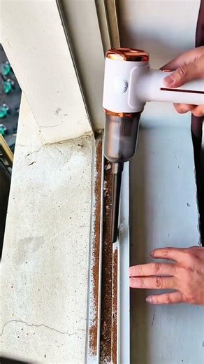 Vacuuming dirt from window track with handheld cleaner