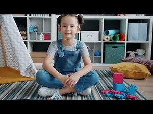 Slow motion portrait of cheerful girl sitting on floor in nursery room smiling looking at camera