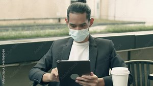 Asian businessman using a tablet checking email while sitting in the coffee shop.
