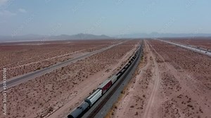 Aerial of a freight train travelling through the arizona desert. Freight supply train aerial. Ground transportation in rural America. Texas desert train.