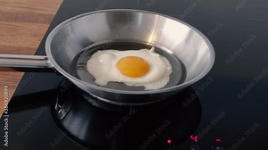 Frying an Egg. Slow zoom into a close up of an egg frying in a frying pan.
