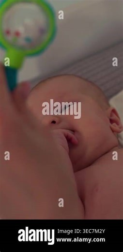 Newborn baby lies on back, exploring fingers and thumb in mouth, close-up shot Stock Video Footage - Alamy