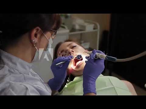 Dentist polishing and varnishing a girl's teeth