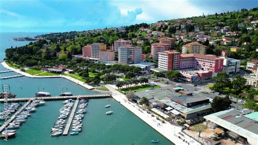 Portorož is a vibrant tourist destination nestled along the Slovenian Riviera, renowned for its pristine beaches, luxurious resorts, and vibrant atmosphere captured by drone