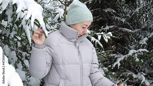 a pretty woman takes a selfie on her smartphone in a snowy forest near a Christmas tree. beautiful snowy winter in the spruce forest. the beauty of nature