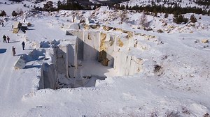Snowy marble quarry seen from above, rocks sculpted by cutting, contrasting with winter environment