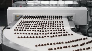 Automated chocolate production line on conveyor belt in confectionery factory.