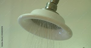 Slow motion medium closeup of a shower as the water turns on, runs for a moment, shuts off and then drips water.