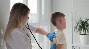 The doctor listens to the breathing of a little boy through a stethoscope. Pediatrician with stethoscope listens to the lungs of a child with bronchitis and cough