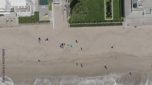 Aerial view gradually ascending from Malibu Beach, revealing the stunning coastal landscape with waves caressing the shoreline and beachfront homes lining the picturesque coast of California