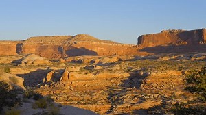 Establishing shot of mountain trail with red rocks background in Monitor and Merrimas View Area, Canyonland National Park, Utah, North America. Day time on October 2023. Still camera view. ProRes 422