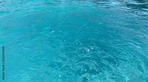 Sky blue water in a swimming pool with light reflections. Sunlight refraction on clear turquoise surface of a swimming pool. Relaxing transparent flowing water. Caustic moving turquoise pattern.