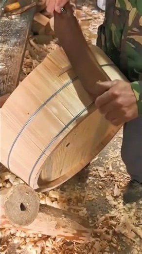 Skilled craftsman shaping wooden bucket using traditional hand tool