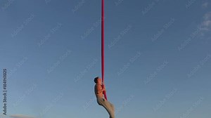 Male aerial acrobat shows tricks in the sky.