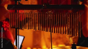 A set of bar bells illuminated by a warm golden light. Bar Chimes on a drum set. The stage is illuminated with soft diffused light. Symphonic concert