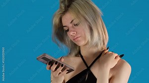 Lady reads nice message on phone with face lighting up with joy. Young woman gazes at device screen clearly delighted by seeing warm message