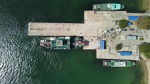 Ferry boat crossing the sea, carrying cars and passengers. Cars drive off the deck onto the port. Top-down aerial drone view Ferry on the lake, transporting cars. deck of a boat carrying vehicles.