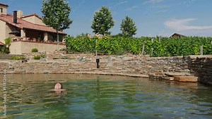 woman relaxing the countryside in natural swimming pool from stone - Tuscany, Italy. Happy woman stay in water and smile
