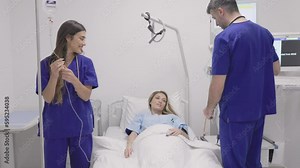 Hospital Ward: Friendly Doctor and nurse taking care of Beautiful Caucasian Female Patient Resting in Bed. Physician explains Test Results. Woman Recovering after Successful Surgery