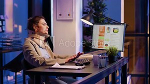 Businesswoman wearing cervical neck collar in office, analyzing diagrams to create financial report. Injured corporate worker planning analytics typing data late at night in company office.