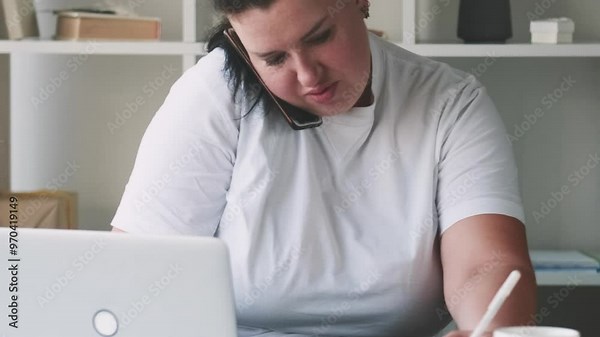 Multitask work. Busy secretary. Tireless overweight woman managing hard job assigning business task taking notes talking on phone in office.