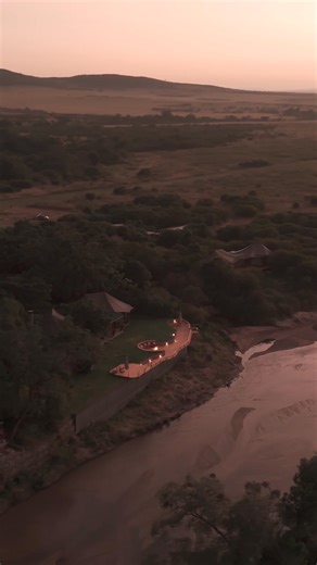 Elephants and their calves take a drink while slowly making their way past the deck at Sala’s Camp, with views stretching across the Masai Mara. | The Safari Collection