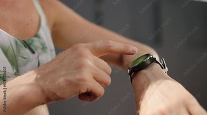 Redhead female athlete checks fitness smart watch in sunny tropical outdoor gym. Professional sportswoman monitors health stats, training performance on wearable tech during workout. Slow motion.