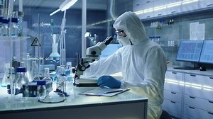 In a Secure High Level Research Laboratory Scientist in a Coverall Adjusts Samples in a Petri Dish with Pincers and then Examines Them Under Microscope. Shot on RED EPIC-W 8K Helium Cinema Camera.