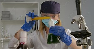 A lab worker is mixing components in a flask and observing their reaction. On a front plan microscope and flask with chemical reactions. Experiments in the laboratory. 4K
