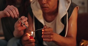 Heroin, injection and couple with addiction in home for substance abuse, overdose or needle opoids. Spoon, syringe and flame lighter for cocaine craving with people together at illegal drug house.