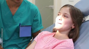 Cute little girl having a dental checkup, talking with dentist