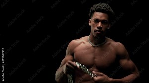 Muscular man showing muscles and holding a chain. African American male posing against black background.