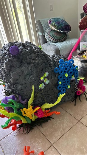 Coral Reef DYI : materials: empty boxes; Pool noodles in bright colors; insulation foam; gray and other bright color spray paint ; foam ball, tooth picks; wood dowels; leis…. Tape the boxes together. U can add craft paper to change the boxy shape. Cover all boxes surface with insulation foam. This should be done in stages, Meaning that u need to let dry and apply again until u have the desire shape . In between waiting cut the pool noodles. To get the sea weed, cut put noodles (preferably w a he