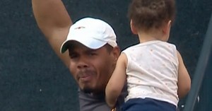 Fan baseball catches while holding babies