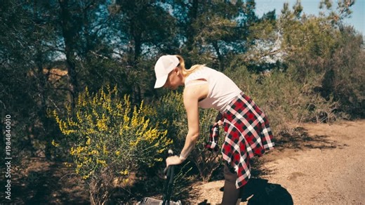 Fit woman untying plaid shirt after Nordic walking exercise session in beautiful park, cooling down after workout. Concept of fitness, recovery, healthy lifestyle, outdoor training and wellbeing