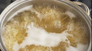 Process of cooking pasta. Spaghetti is cooked in boiling water in large pan, close-up.
