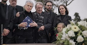 Funeral, cemetery and family with American flag for soldier for respect, ceremony and memorial service. Sad, depression and people by coffin in graveyard mourning military, army and veteran hero