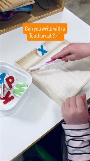 Sensory writing trays are a fun multi-sensory way to practice making letters, numbers, lines, and shapes. This has a thin layer of flour at the bottom. Students choose a letter token and then use a toothbrush to write the letter in the tray. Give it a little shake, then start again! More pictures and ideas here: https://playtolearnpreschool.us/category/literacy/learn-to-write/ #preschoolteacher #preschoolactivities #earlychildhoodeducation #preschoolideas #learntowrite | Play to Learn Preschool