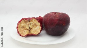 Super time lapse of two apples dehydrating and going bad after placing on porcelain white plate and left in lightbox or under controlled lighting condition against white background for 21 days