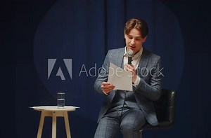 StandUp cafe, comedy concert. Man telling jokes on stage. Male comedian speaks with audience using microphone, humorous monologue. Mentor coach training. Public speaking masterclass.