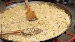 Cooking a traditional dish Valencian cuisine Fideua de Marisco during a street holiday in Spain. Close-up image