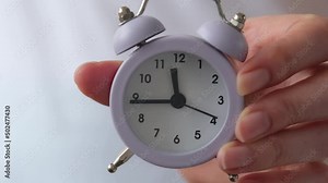 Women's hands hold an alarm clock. Then the girl shows the alarm clock to the lens. A reminder of a time, of some event. Medical checkup reminder and more