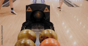 Close-up view of balls returning during bowling game. Legs of players on background and balls during game in bowling