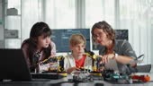 A team of young engineers collaborates on building a robotic...