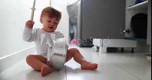 Baby boy hitting metal kitchen utensil on floor. One year old toddler drumming pans and pots
