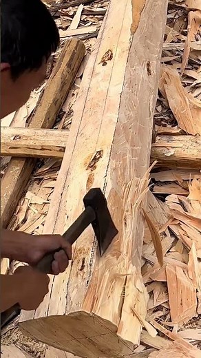 Old carpenter using an axe to make beams for the wooden house