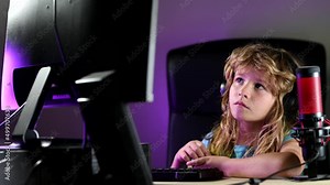 A little boy child uses a desktop at night, a child with computer screen in the room with neon lightning.